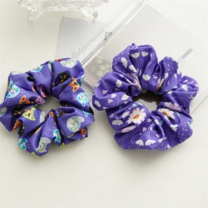 Satin scrunchies detail featuring purple floral prints and colorful cat head patterns