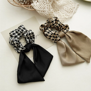 Detail of houndstooth scrunchie with long satin ribbons in black and khaki tones