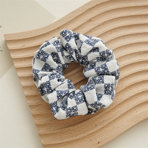 Detail of blue and white checkered scrunchie with floral pattern on wooden tray