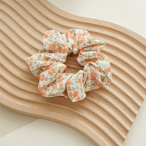 Vista dettagliata di un elastico in chiffon floreale arancione su supporto in legno