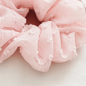 Close-up detail of pink seersucker scrunchie fabric with 3D dots and soft texture