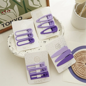 Minimalist purple matte hair clips set with various geometric shapes on display card