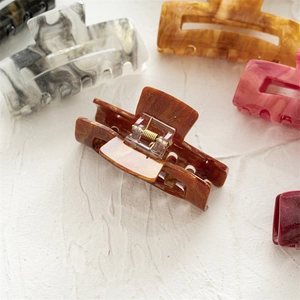 Detailed view of large marble texture hair claws in various elegant acrylic colors