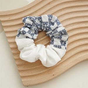 Detail of blue and white checkered fabric scrunchie with floral pattern on wooden tray