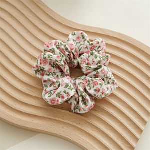Dettaglio dell'elastico in chiffon floreale con piccoli fiori rossi su legno
