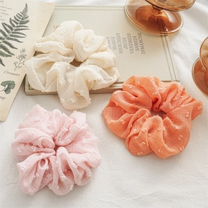Three oversized seersucker hair scrunchies in cream white, light pink, and vibrant orange