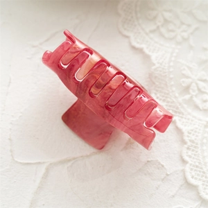 Macro detail of rectangle acrylic hair claw clip with marble texture and glittery pink finish