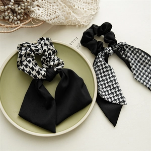 Detail of elegant houndstooth and black bow scrunchies on a ceramic decorative tray