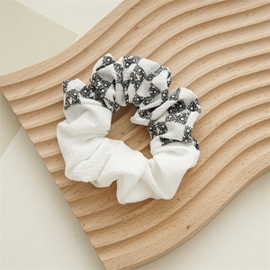 Close-up of spring fabric scrunchie with daisy print and white pleated patchwork details