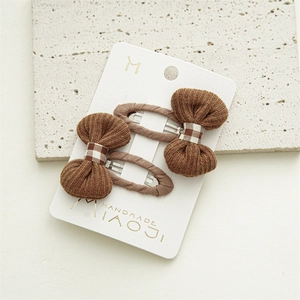 Close-up of handmade caramel knit bow hair clips on branded cardstock display