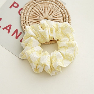 Détail du chouchou en seersucker à carreaux jaunes et blancs avec motifs de marguerites