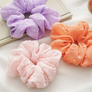 Detail of three pastel seersucker hair scrunchies with swiss dots and grid texture