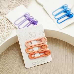 Close-up of safety pin hair clips in pastel purple and blue on a vintage wooden tray