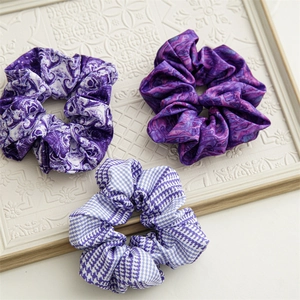 Dettaglio di tre scrunchies in raso blu pervinca con motivi marmorizzati e pied-de-poule