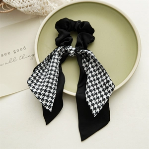 Detailed view of black satin scrunchie with houndstooth ribbon on decorative tray