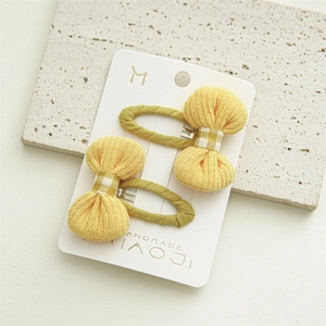 Detail of yellow knitted bow hair clips on display card with handmade branding labels
