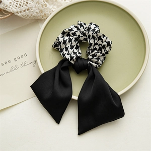 Detail of black and white houndstooth scrunchie with long ribbon bow on ceramic plate