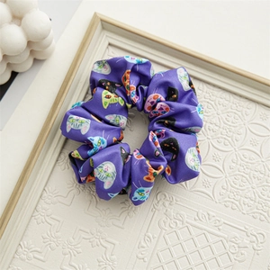 Detail view of purple satin scrunchie with cute cartoon cat prints on white frame