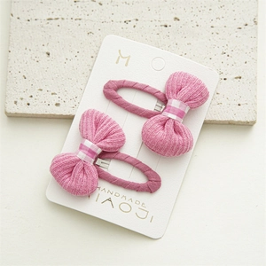 Detail of pink bow hair clips with striped fabric and purple fabric-wrapped duckbill clips