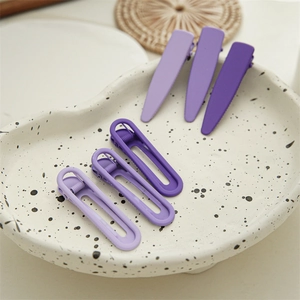 Detailed view of matte purple hair clip set in various shapes on a ceramic tray