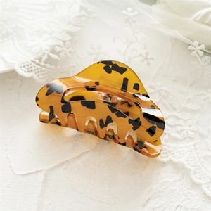 Detail view of square acrylic hair claw clip with amber leopard print pattern on lace