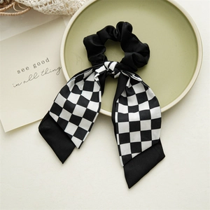 Detail of checkered bow hair scrunchie with long ribbon on a decorative tray