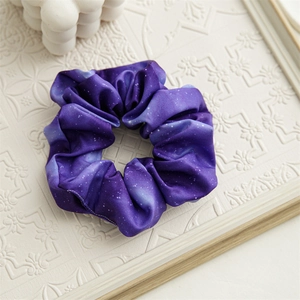 Dettaglio dell'elastico per capelli in raso blu pervinca con stampa galassia stellata