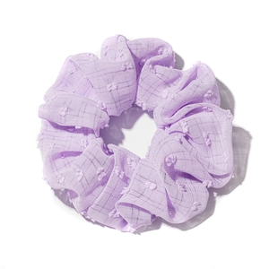 Lavender seersucker scrunchie with dot texture and small pom-pom details on white background
