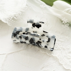 Macro detail of square marble pattern hair claw clip made of polished acrylic acetate