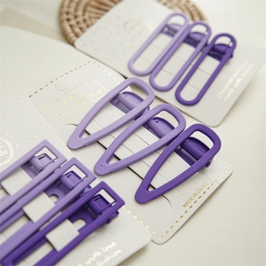 Detailed macro view of purple matte hair clips in various geometric shapes on a white card