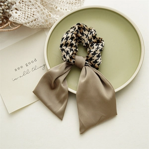 Detail of checkered bow hair scrunchie with long ribbons on a vintage tray