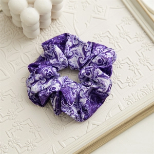 Dettaglio ravvicinato di elastico scrunchie in raso con motivo marmorizzato viola e bianco