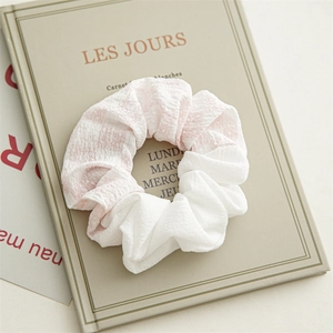 Détail d'un chouchou à carreaux rose et blanc avec motif floral sur un livre