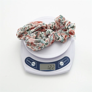 Floral hair scrunchie with bow detail weighing 12.2g on a white scale closeup