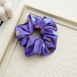 Detail of satin scrunchie with blue heart patterns on soft lavender fabric texture