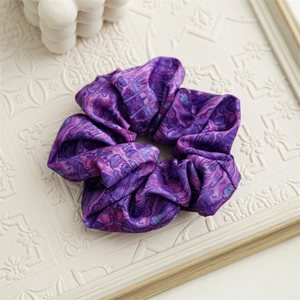 Dettaglio dell'elastico per capelli in raso viola con stampa a cielo stellato