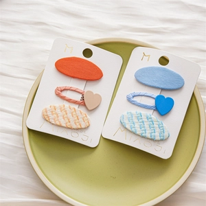 Detail view of colorful cute children's hair clips on a white card in a green plate