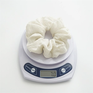 Detailansicht eines weißen Haargummis mit einem Gewicht von 7,0 g auf der Waage