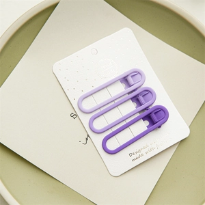 Three purple matte metal duckbill hair clips displayed on a white textured card