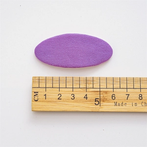 Close-up of a 5cm purple fabric oval hair clip with woven texture on a ruler