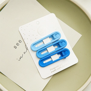 Close-up of blue gradient hollow oval hair clips set with a matte finish on a green tray