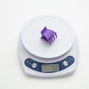Détail d'une petite pince à cheveux violette mate pesant seulement 5,6 g sur une balance