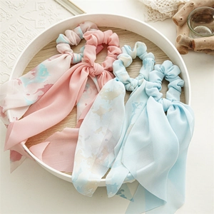 Detail showing chiffon bow hair scrunchies with floral patterns in soft pastel colors
