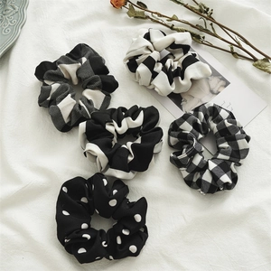 Detail view of five-piece black and white patterned scrunchies on white linen background