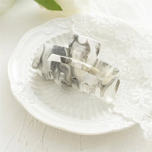 Detailed macro view of square acrylic hair claw with grey marble texture and glitter