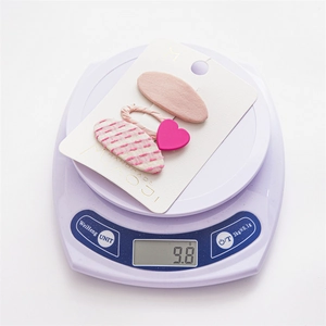 Weight measurement of cute handmade pink heart and oval hair clips on a scale