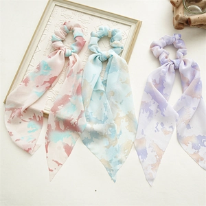 Detailed macro shot showing three vibrant gradient floral chiffon hair scrunchies with ribbons