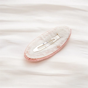 Back view of pink fabric oval hair clip with silver BB clip on soft textured fabric
