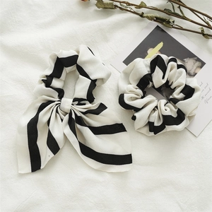 Detail of black and white striped scrunchies with bow tie on soft white fabric background