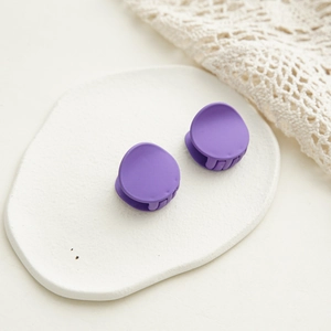 Détail de deux mini-pinces à cheveux violettes mates sur un socle en pierre décorative
